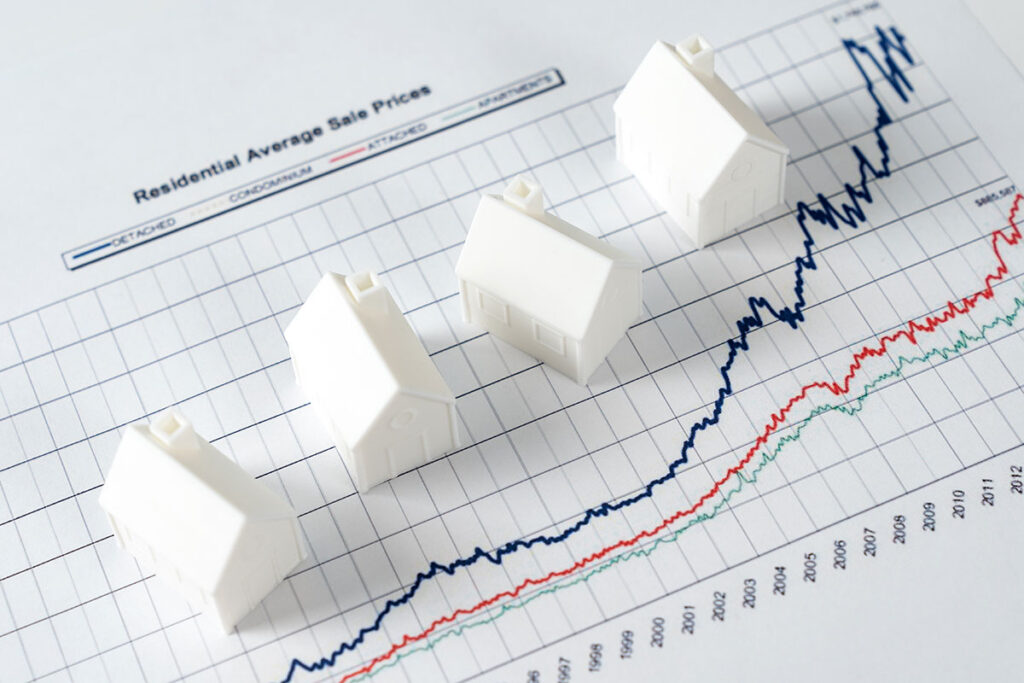 miniature white houses on graph chart of real estate market prices